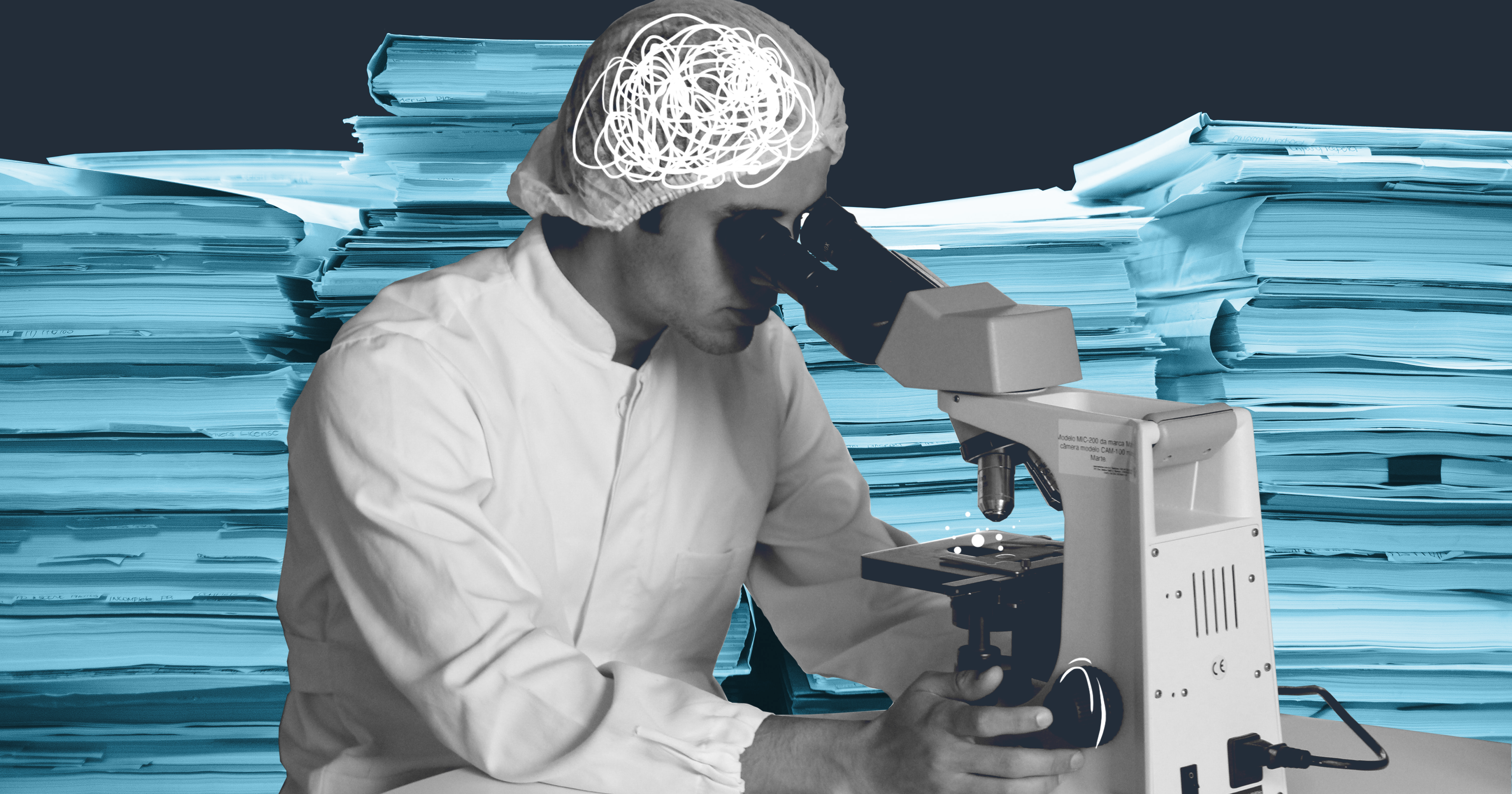 Scientist looks into a microscope and is surrounded by paperwork